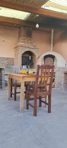 een houten tafel en een bank voor een bakstenen oven bij Hospedaje San Cayetano in Maimará