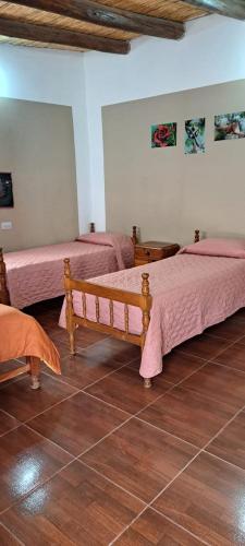 twee bedden in een kamer met roze lakens bij Hospedaje San Cayetano in Maimará