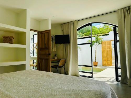 タマリンドにあるLas Guapas Villas Tamarindoのベッドルーム1室(ベッド1台付)、スライド式ガラスドアが備わります。