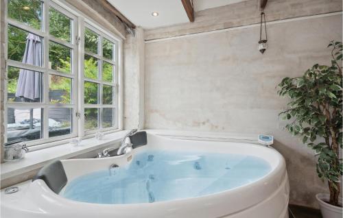 a large white tub in a bathroom with windows at 2 Bedroom Pet Friendly Home In rskbing in Ærøskøbing