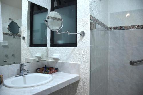 a bathroom with a sink and a mirror and a shower at Rosario Hotel in San Cristóbal de Las Casas