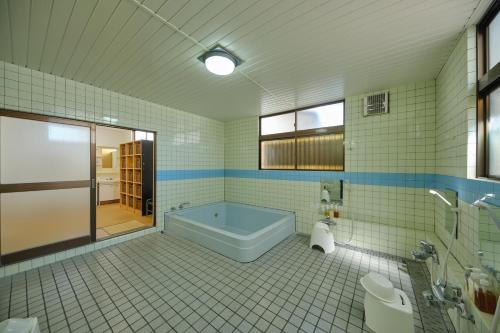 a bathroom with a tub and a toilet and a sink at 芙蓉山居煙霞ー元富士の屋旅館ー in Fujikawaguchiko