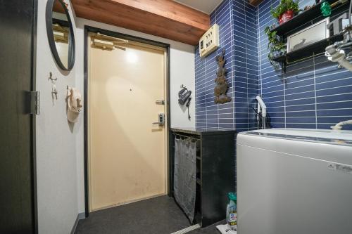 ein Bad mit blau gefliesten Wänden und einer Tür in der Unterkunft Cooee Sapporo in Sapporo