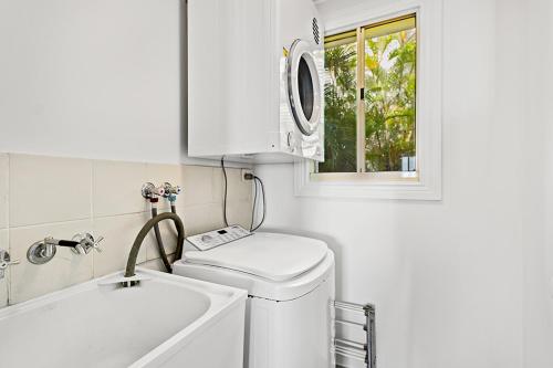 uma lavandaria branca com uma máquina de lavar roupa e uma janela em Airlie Hasta Manana em Airlie Beach