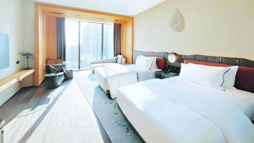 um quarto de hotel com duas camas e uma grande janela em The Westin Yantai em Yantai