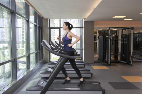a woman running on a treadmill in a gym at The Meixi Lake, Changsha Marriott Executive Apartments in Changsha