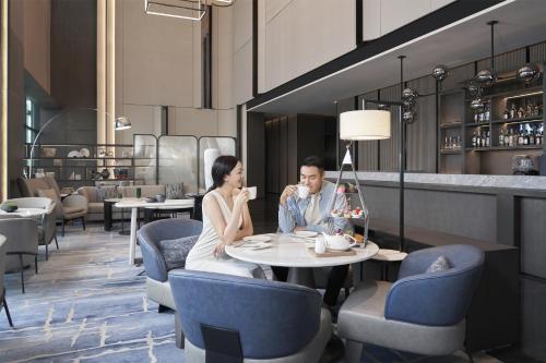 a man and woman sitting at a table in a restaurant at The Meixi Lake, Changsha Marriott Executive Apartments in Changsha