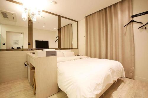 a bedroom with a large white bed and a mirror at Hotel Lassa in Seoul