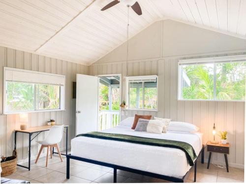 a bedroom with a bed and a desk and windows at Monstera Bungalow, Spacious, King Bed, Big Kitchen in Keaau