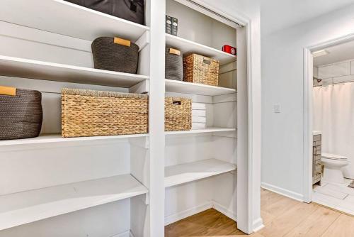 a walk in closet with white shelves and baskets at Savannah Place: Mid-Century Modern 3 Bedroom Home in Savannah