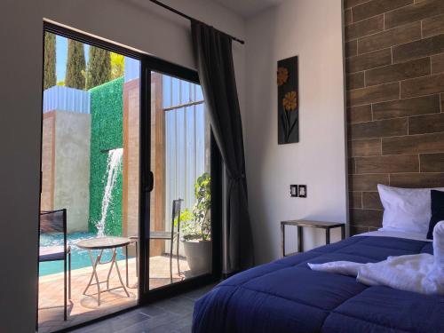 um quarto com uma cama azul e uma porta de vidro deslizante em Antia Valle de Guadalupe em Valle de Guadalupe