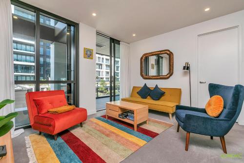 a living room with two chairs a couch and a mirror at QV Stays Stylish Wynyard Escape in Auckland