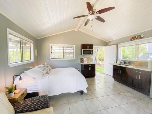 Surf Getaway, Queen Bed, Private Lanai في Keaau: غرفة نوم بسرير أبيض ومروحة سقف