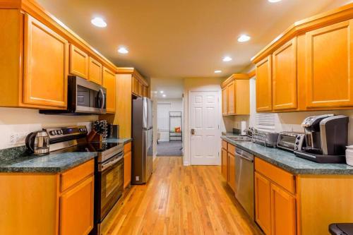 a large kitchen with wooden cabinets and wooden floors at Saratoga Serenity: Charming Rental Nearby Downtown in Saratoga Springs