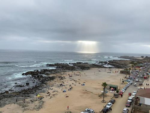 einen Strand mit einer Menschenmenge und einem Regenbogen in der Unterkunft Departamento Vista al Mar el Tabo in El Tabo