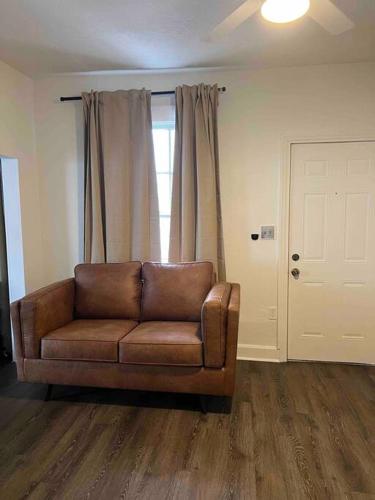 a brown leather couch in a living room with a window at Lovely historic apt near Amelia Arena + Hyde Park in Tampa