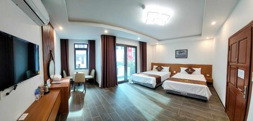 a bedroom with two beds and a flat screen tv at Swan Motel in Ha Long