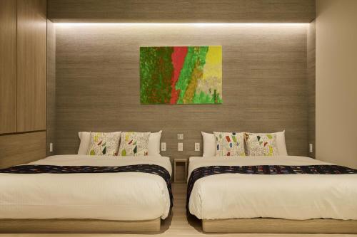 a bedroom with two beds and a painting on the wall at fav HIROSHIMA HEIWAODORI in Hiroshima
