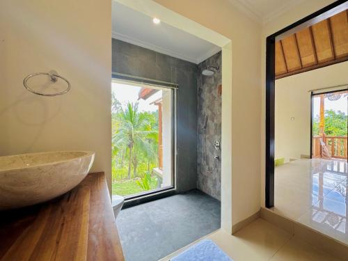 La salle de bains est pourvue d'un grand lavabo en pierre et d'une fenêtre. dans l'établissement Green Coco Suite, à Nusa Penida