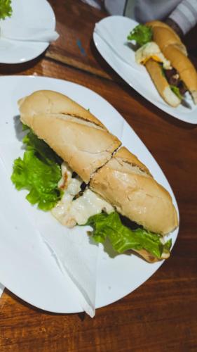 a sandwich on a white plate on a table at Pousada no Sana Donna Leda in Sana
