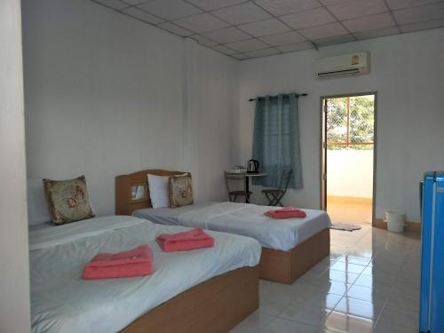2 łóżka w białym pokoju z oknem w obiekcie Alongkon Mansion w mieście Sakon Nakhon