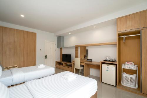 a hotel room with two beds and a desk at Riski Residence Ngamwongwan in Nonthaburi