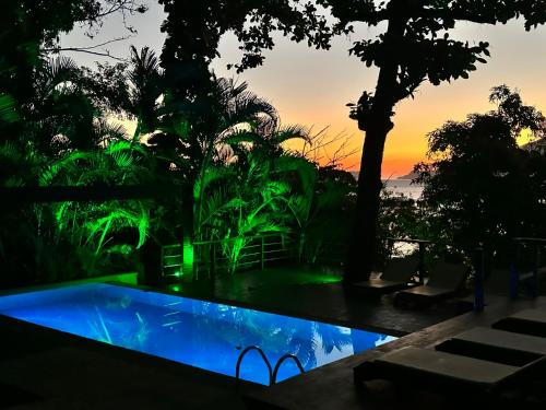 a pool with green lights in front of a sunset at Casas Do Mar in Ilhabela