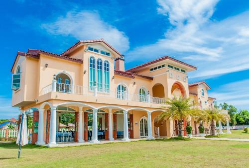a large house with palm trees in front of it at Paeporpiang (เพพอเพียง) in Ban Nai Rai