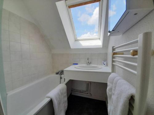 La salle de bains est pourvue d'un lavabo, d'une baignoire et d'une fenêtre. dans l'établissement Maison cosy 3 pièces avec terrasse à 800m de la plage - Wifi, lave-vaisselle, parking public - FR-1-477-238, à La Trinité-sur-Mer