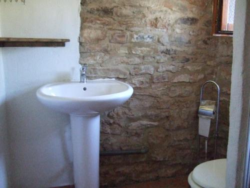 a bathroom with a white sink and a stone wall at Casita Joya in Perelló