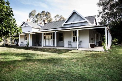 a white house with a porch and a yard at The Glen Farmhouse on Ovens River in Wangaratta