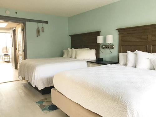 duas camas num quarto de hotel com lençóis brancos em Flip Flop at Compass Cove em Myrtle Beach
