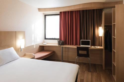 a hotel room with a bed and a desk with a computer at ibis Angers Centre Chateau in Angers