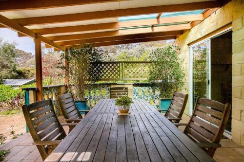 a wooden table and chairs on a patio at Camellia Cottage - Country Rustic Charm Close to Forest and Town in Margaret River Town