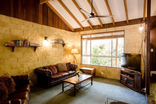 a living room with a couch and a table at Camellia Cottage - Country Rustic Charm Close to Forest and Town in Margaret River Town