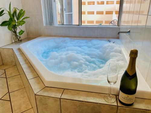 a hot tub with a bottle of wine and a wine glass at Eden House Retreat in Yungaburra