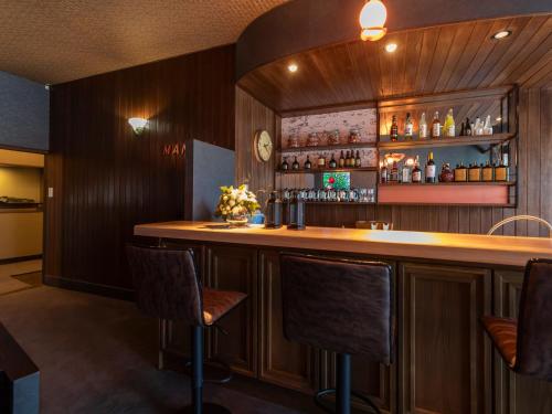 a bar in a restaurant with wooden walls and chairs at Tabist Nanki Shirahama Ryokan Mantei in Shirahama