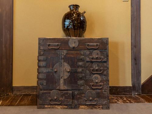 a wooden chest with a vase on top of it at Tabist Nanki Shirahama Ryokan Mantei in Shirahama