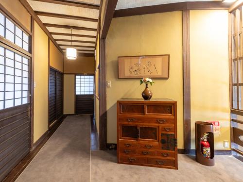 a hallway with a dresser and a vase on top of it at Tabist Nanki Shirahama Ryokan Mantei in Shirahama