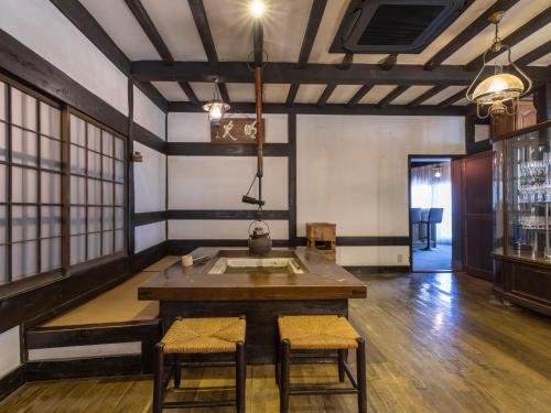 a room with a table and chairs in a room withwindows at Tabist Nanki Shirahama Ryokan Mantei in Shirahama