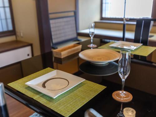 a table with a plate and two wine glasses on it at Tabist Nanki Shirahama Ryokan Mantei in Shirahama