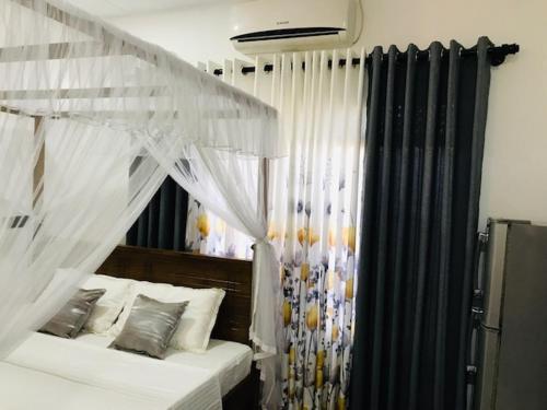 1 dormitorio con cama con dosel y cortinas en SUMITH VILLA, en Mirissa