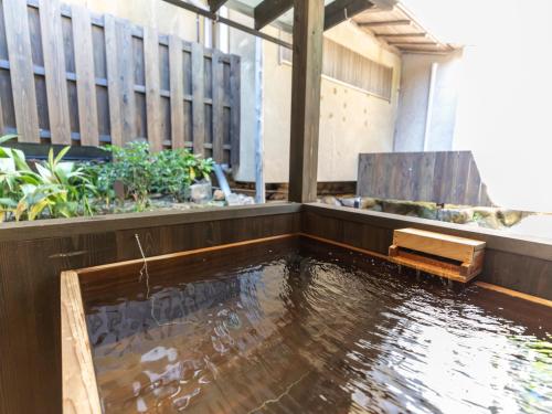 a pool of water with a bench in a building at Tabist Nanki Shirahama Ryokan Mantei in Shirahama