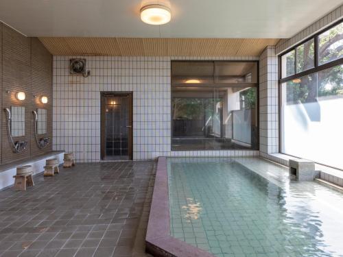 a swimming pool in a building with a house at Tabist Nanki Shirahama Ryokan Mantei in Shirahama