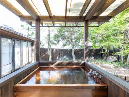 a koi pond in a house with a pergola at Tabist Nanki Shirahama Ryokan Mantei in Shirahama