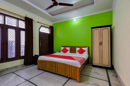a bedroom with green walls and a bed with red pillows at Super OYO Flagship Rudraksh Hotel in Rāmnagar