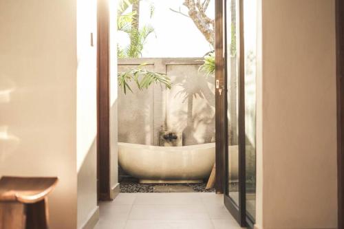 een badkamer met een bad en een raam bij Villa Puri Kembar in Ubud