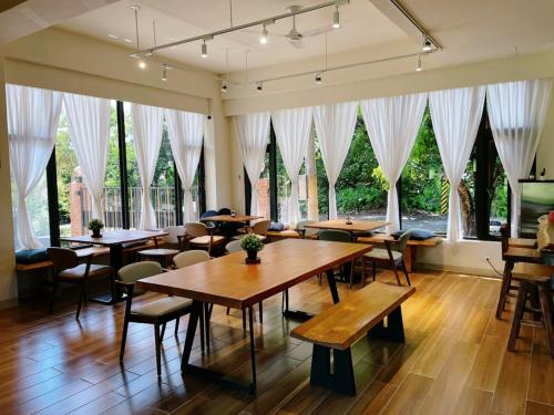 a restaurant with tables and chairs and large windows at Taroko 767 Farm B&B 太魯閣767農莊民宿 in Xiulin