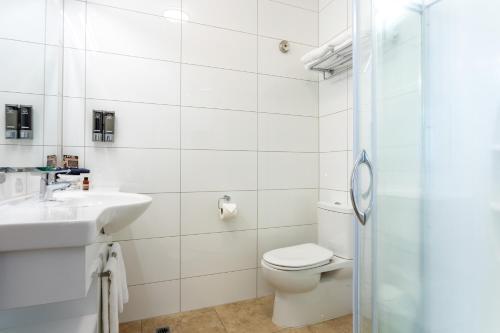 a bathroom with a toilet and a sink and a shower at Tuakau Hotel in Tuakau