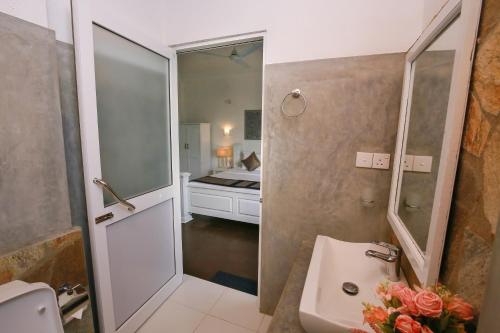 a bathroom with a sink and a toilet and a mirror at Ceylon House By Sunrise in Ella